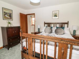 a bedroom with a wooden bed and a wooden dresser at Thrushel Cottage in Lifton