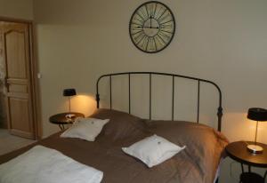 a bedroom with a bed with a clock on the wall at Le Clos de l'Eglise - Inès in Giverny