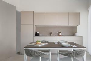 a white kitchen with a table and two chairs at Pareus Beach Resort in Caorle