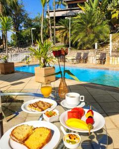 a table topped with plates of food next to a pool at Pousada Reserva Penedo in Penedo