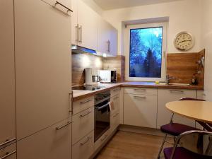 cocina con armarios blancos, mesa y ventana en Flensburg Ferienwohnungen Apartment 1, en Flensburg