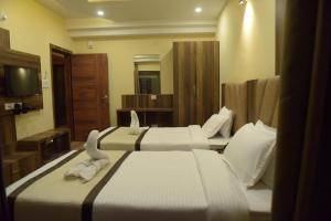 een hotelkamer met 2 bedden en een televisie bij Hotel Royal City in Siliguri