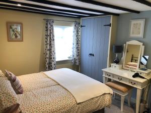 a bedroom with a bed and a desk and a window at Oriel Cottage in Pevensey