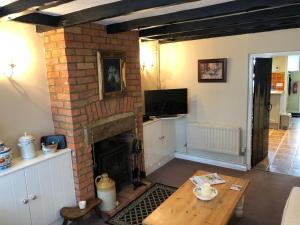 a living room with a brick fireplace and a table at Oriel Cottage in Pevensey