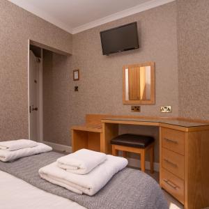 a bedroom with a desk and a bed with towels at Lorimer House in St Andrews