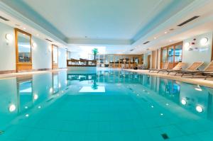 a large swimming pool with chairs in a building at Thon Hotel Residence Parnasse Aparthotel in Brussels