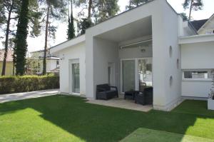 a white house with two chairs on a lawn at Bori Villa Siófok in Siófok