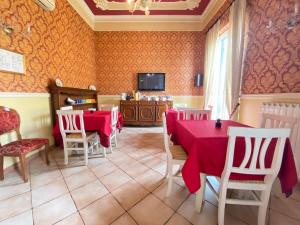 uma sala de jantar com mesas e cadeiras vermelhas e uma televisão em B&B Dimora Annulina em Palermo