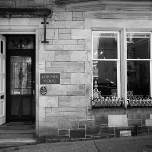 um edifício de tijolos com uma placa em frente a uma loja em Lorimer House em St Andrews