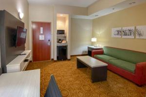 a hotel room with a green couch and a table at Sleep Inn & Suites Springdale West in Springdale