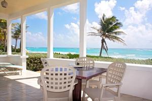 a dining room with a table and chairs and the ocean at This is a beachfront 3 bedroom, 3 bathroom villa, family-friendly activities in Christ Church