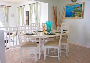 a dining room with a white table and chairs at This is a beachfront 3 bedroom, 3 bathroom villa, family-friendly activities in Christ Church