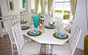 a white dining room with a white table and chairs at This is a beachfront 3 bedroom, 3 bathroom villa, family-friendly activities in Christ Church