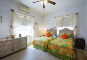 a bedroom with two beds and a ceiling fan at Welcome to the unpretentious and breezy Graceville, steps away from the beach in Saint James