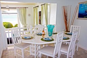 a white dining room with a white table and chairs at Silver Sands Beach Villas are great for family-friendly activities surfing in Christ Church