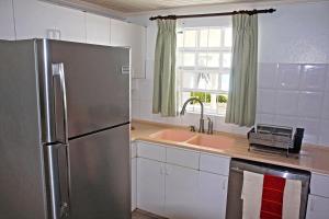 a kitchen with a stainless steel refrigerator and a sink at Silver Sands Beach Villas are great for family-friendly activities surfing in Christ Church