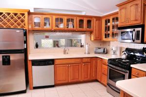 a kitchen with wooden cabinets and stainless steel appliances at Seagaze beach house is perfect for family, a few steps to the beach in Saint James