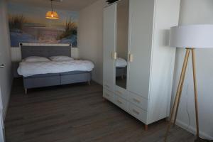 een slaapkamer met een bed en een dressoir met een spiegel bij Vier Jahreszeiten 4JZ Haus 2 Whg 76 in Großenbrode