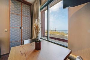 einen Tisch mit einer Vase darauf mit einem Fenster in der Unterkunft Strandhotel Scheveningen in Scheveningen