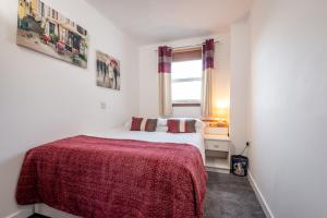 ein Schlafzimmer mit einem Bett mit einer roten Decke und einem Fenster in der Unterkunft 2 Bedroom Apartment in a Quiet Neighbourhood in St Andrews