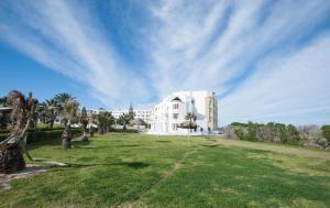 a large white building with palm trees in a field at Thapsus Beach Resort in Mahdia