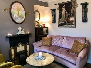 a living room with a purple couch and a candle on a table at Glastonbury Rose Cottage in Glastonbury