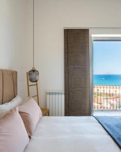 een slaapkamer met een bed en uitzicht op de oceaan bij Matteotti 16 - Suites in Cefalù in Cefalù