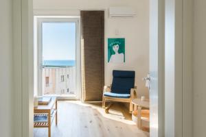 sala de estar con silla azul y ventana en Matteotti 16 - Suites in Cefalù en Cefalù