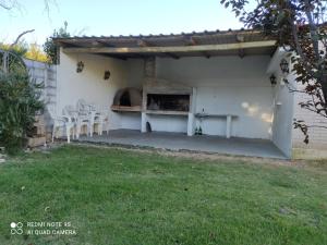 匹里亞波里斯的住宿－Amplia Casa de 2 dormitorios en Piriapolis, a 4 cuadras de Playa San Francisco，一个带白色椅子和比萨饼烤箱的庭院