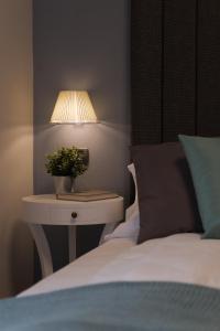 un letto con comodino, lampada e letto bianco di Hotel Milano & Apartments a Miazzina