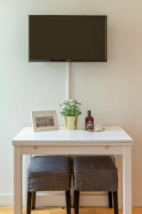 una mesa blanca con dos taburetes y un televisor. en Inside Porto Apartments - Pinheiro, en Oporto