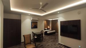 sala de estar con TV de pantalla plana y sofá en The Vilana Hotel Rishikesh en Rishīkesh