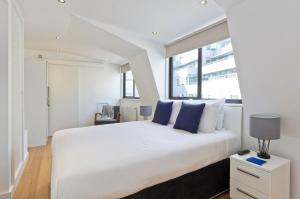 een slaapkamer met een groot wit bed met blauwe kussens bij Red Lion Court by City2Stay in Londen