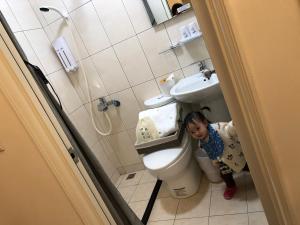 a little girl standing next to a toilet in a bathroom at 漫時光 旅空間 ManLu INN in Jinning