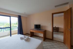 a bedroom with a bed and a desk with a television at Samba Angra dos Reis in Angra dos Reis