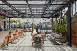 a rooftop patio with chairs and tables and a bar at Masaya Medellin in Medellín