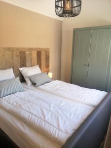 a large white bed in a bedroom with a chandelier at DWC00 - New romantic studio with large terrace in Domburg