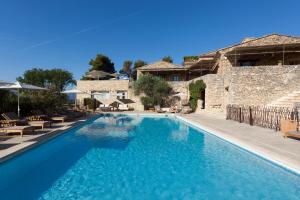 - une piscine d'eau bleue en face d'un bâtiment dans l'établissement Mas des Herbes Blanches Hôtel & Spa – Relais & Châteaux, à Joucas