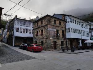 un coche rojo estacionado frente a un edificio de piedra en Habitación Cuadruple con derecho a Barbacoa y patio, en Navia de Suarna