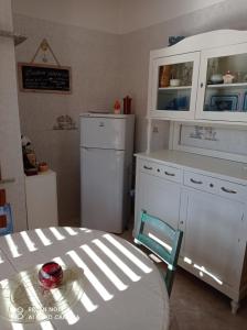 cocina con armarios blancos, mesa y nevera en La Numaba en Corato