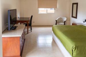 a bedroom with a bed and a desk with a television at Hotel Plaza del Sol in Hermosillo