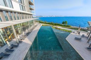 a building with a swimming pool next to the ocean at Posh 2 BR Oceanfront Apt in the Heart of Bluewaters Island in Dubai