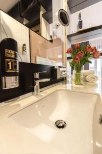 a white bathroom sink with a vase of flowers at 24Seven Hotel Schwabach in Schwabach