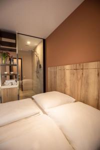 a bedroom with two white beds and a shower at 24Seven Hotel Schwabach in Schwabach