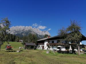 a house in a field with mountains in the background at Pension Sunnbichl in Going am Wilden Kaiser