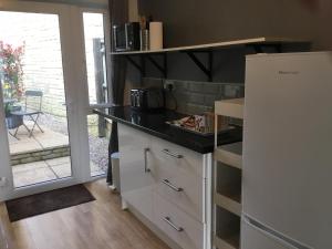 cocina con encimera negra y nevera blanca en Self-contained Apartment en Corsham