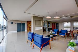 - un hall avec des chaises bleues et une table dans l'établissement Go Inn Betim - MG, à Betim