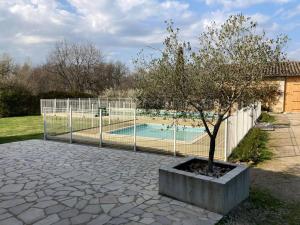 a fence with a tree next to a swimming pool at Camping Fargogne in Puygaillard-de-Quercy +9 photos