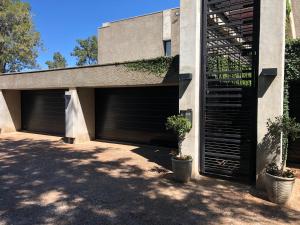 two garage doors on a building with plants at Ten On Lane in Polokwane