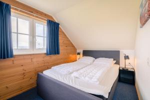 Schlafzimmer mit einem großen Bett und blauen Vorhängen in der Unterkunft Annabella 13 in De Koog